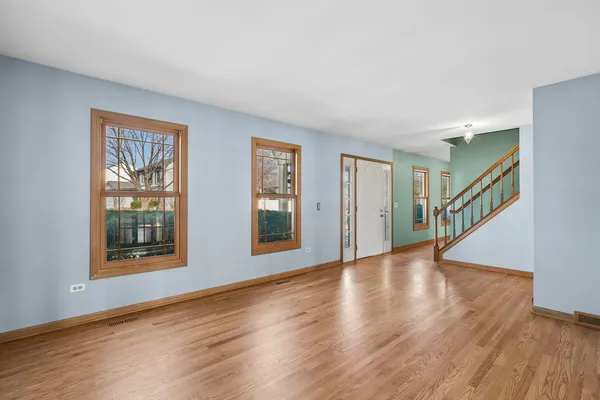 a view of an empty room with wooden floor and windows