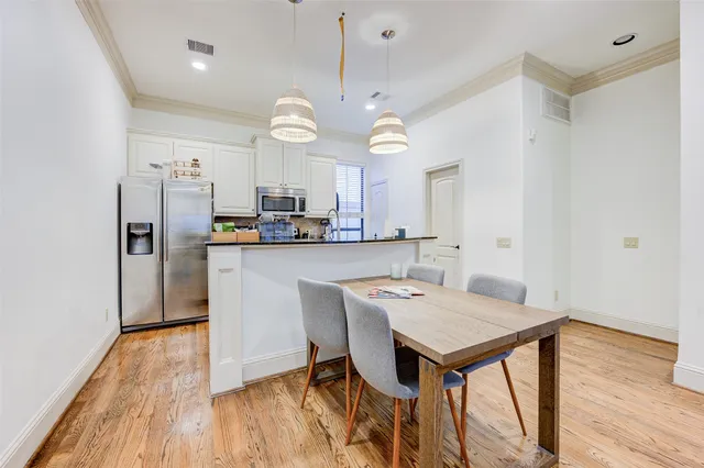 a kitchen with stainless steel appliances a dining table chairs refrigerator and microwave