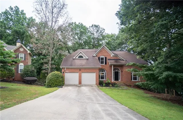 a front view of a house with a yard and trees
