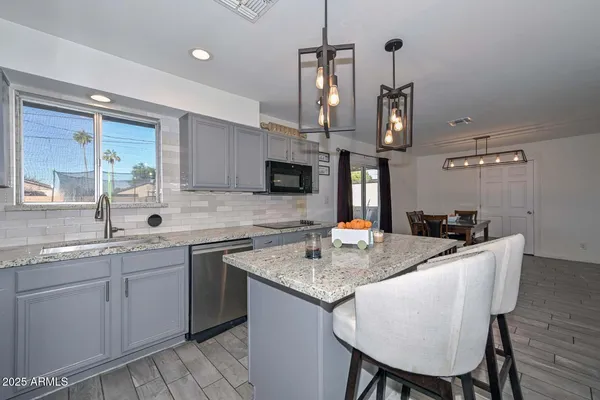 a kitchen with stainless steel appliances granite countertop a sink a stove a kitchen island with chairs and cabinets