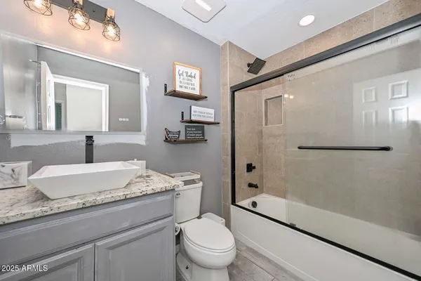 a bathroom with a granite countertop sink a toilet a mirror and shower