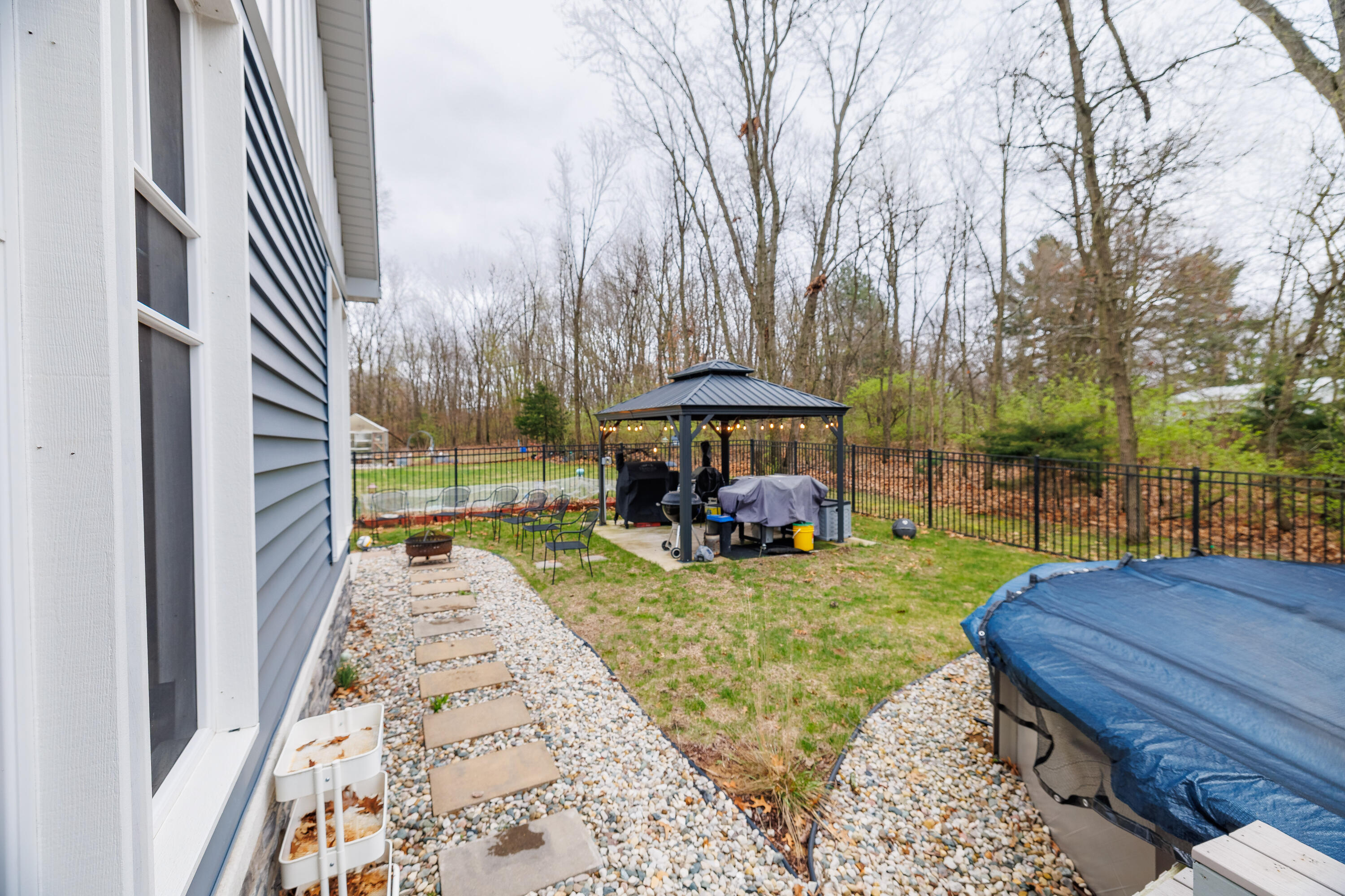 6795 Whispering Woods Drive Demotte, IN 46310 - Photo 11 of 64 a view of a backyard with table and chairs under an umbrella with large trees