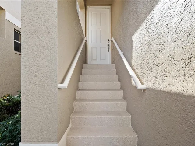a view of staircase with white walls and white door