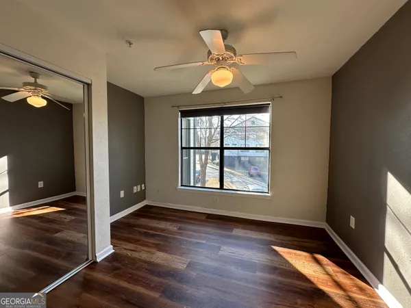 an empty room with wooden floor fan and windows
