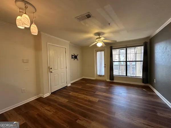 a view of an empty room with wooden floor and a window