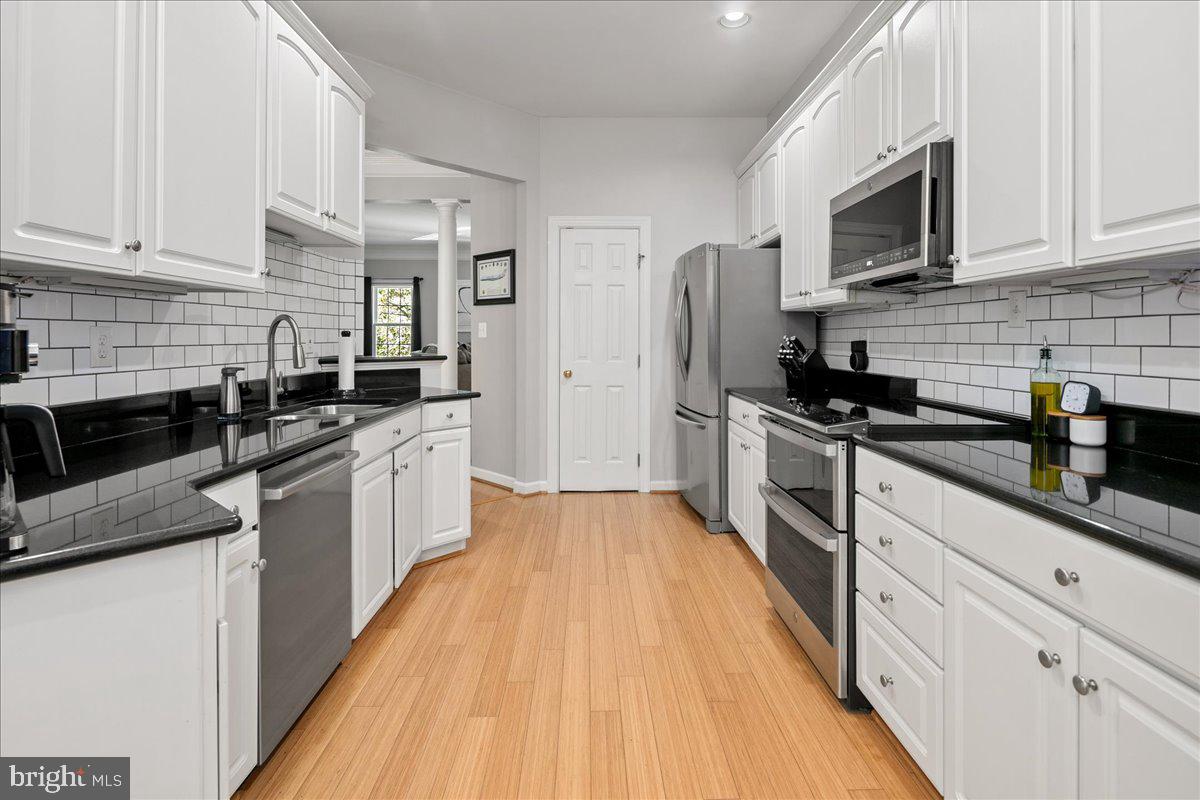 6347 Simmer Circle Springfield, VA 22150 - Photo 17 of 47 a kitchen with stainless steel appliances a sink dishwasher a refrigerator a microwave oven with cabinets and wooden floor