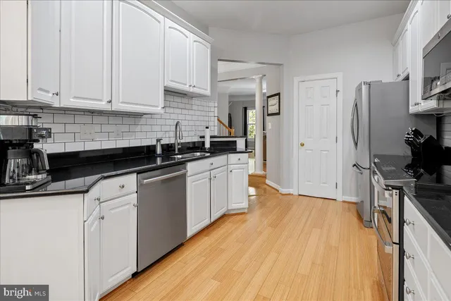 a kitchen with stainless steel appliances a sink dishwasher stove refrigerator and cabinets