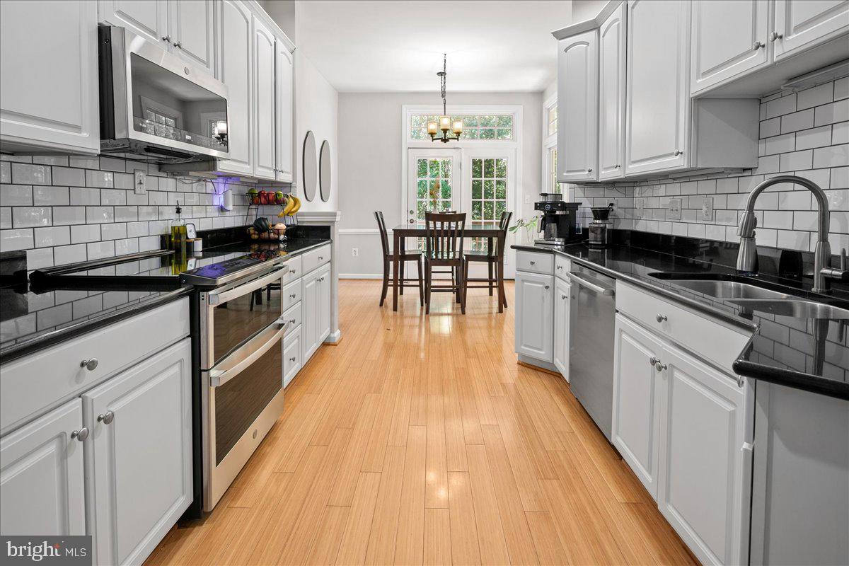 6347 Simmer Circle Springfield, VA 22150 - Photo 20 of 47 a kitchen with stainless steel appliances a sink wooden floor cabinets and a window
