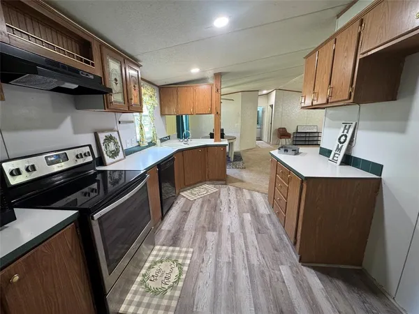 a kitchen with stainless steel appliances granite countertop a stove a sink dishwasher and a microwave with wooden floor