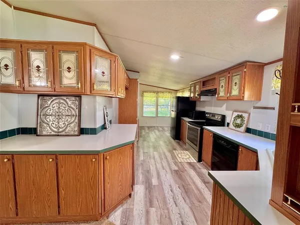 a kitchen with stainless steel appliances granite countertop a refrigerator a sink dishwasher a stove and white countertops with wooden floor