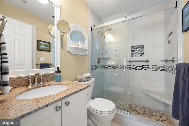 a bathroom with a granite countertop sink a mirror and a toilet