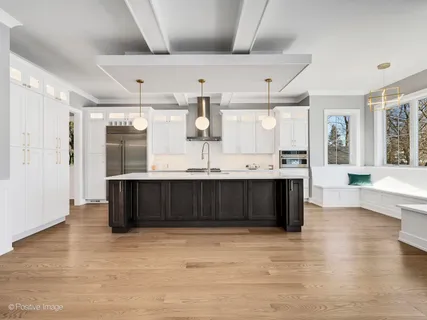 a living room with stainless steel appliances kitchen island granite countertop a large counter top a sink and a wooden floors