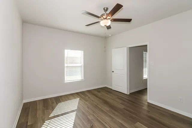 an empty room with wooden floor and windows