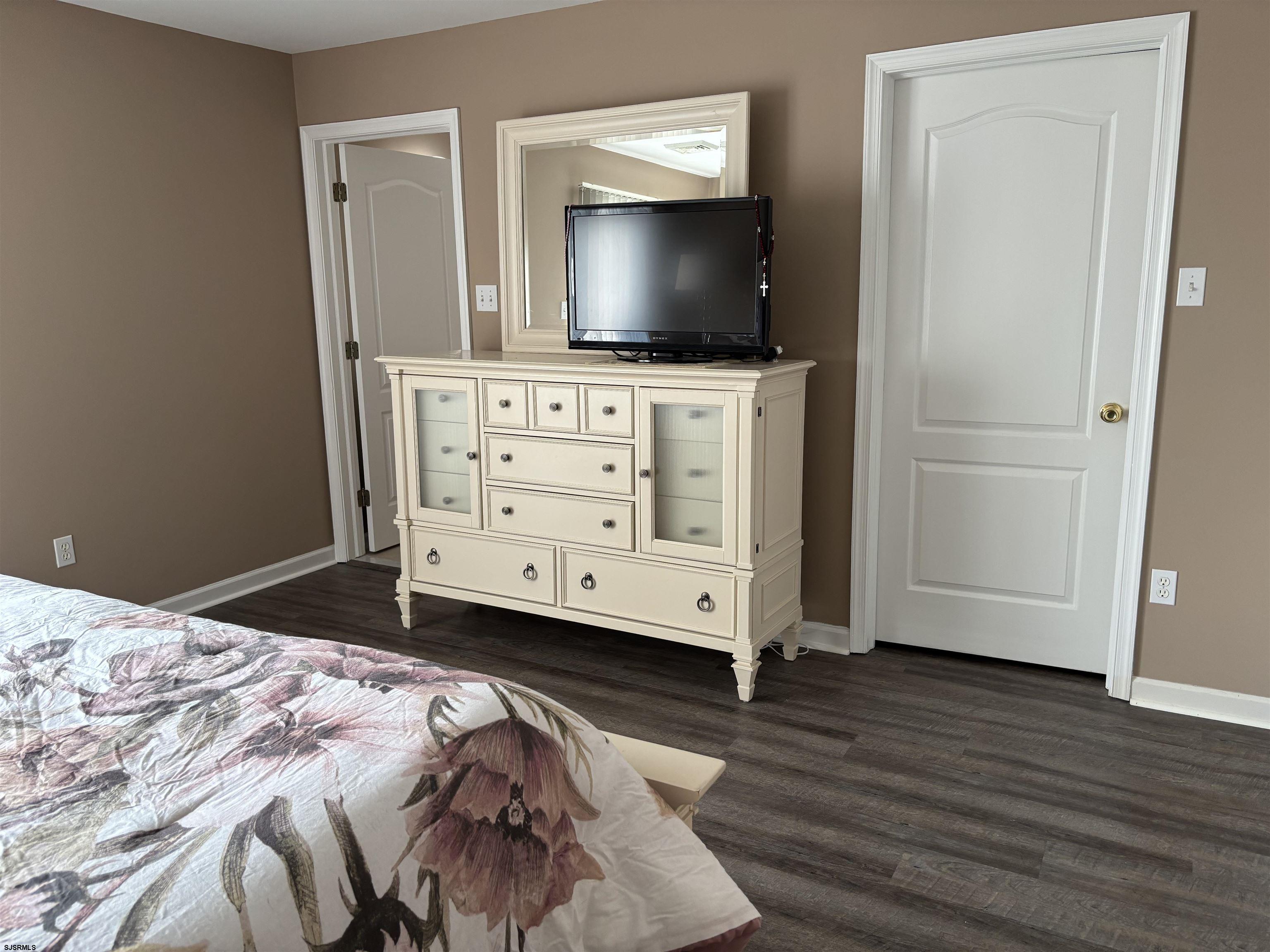 66 Sailfish Drive Brigantine, NJ 08203 - Photo 21 of 24 a bedroom with a flat screen tv on dresser and a wooden floor