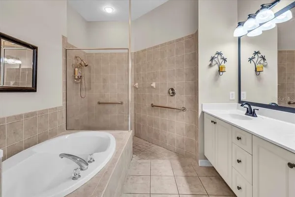 a bathroom with a tub sink a mirror a shower and vanity
