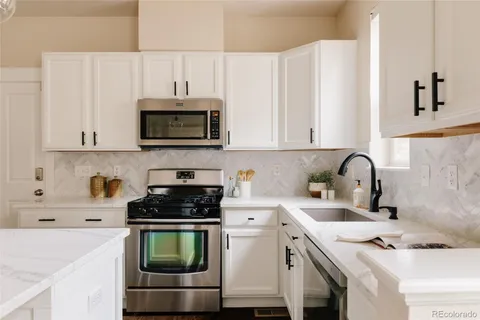 a kitchen with granite countertop a stove a sink and a microwave