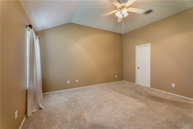 an empty room with a ceiling fan and a window