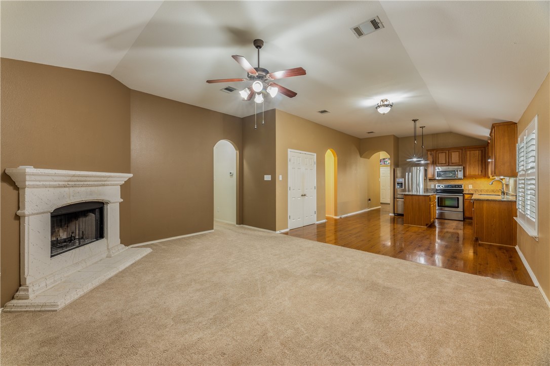 114 Inman Drive Hutto, TX 78634 - Photo 9 of 20 a view of an empty room with kitchen and a fireplace