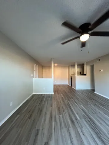 an empty room with wooden floor chandelier fan and windows