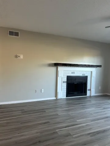 a view of empty room with wooden floor and fireplace