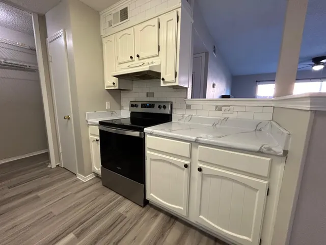 a kitchen with stainless steel appliances white cabinets and a refrigerator