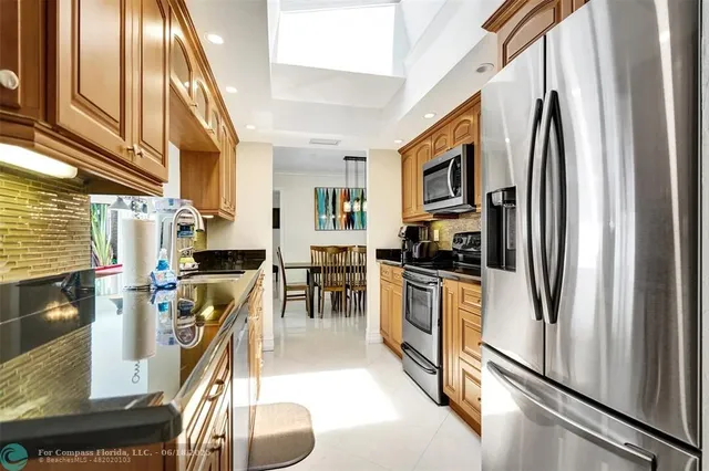 a kitchen with stainless steel appliances granite countertop a refrigerator a oven a stove and a sink