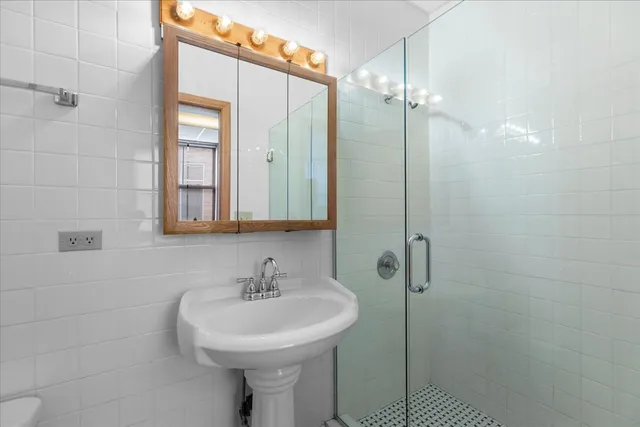 a bathroom with a sink shower and a mirror