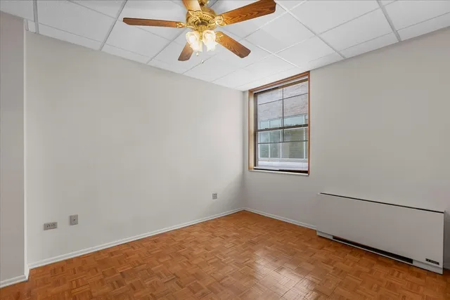an empty room with windows and fan