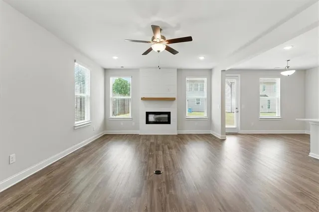 an empty room with wooden floor fireplace and windows