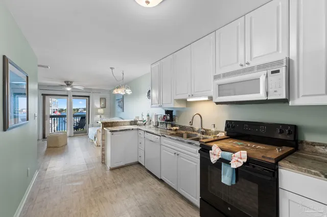 a kitchen with stainless steel appliances granite countertop a stove a sink dishwasher and cabinets with wooden floor