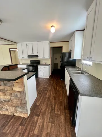 a kitchen with kitchen island granite countertop a sink a stove top oven a counter space and cabinets