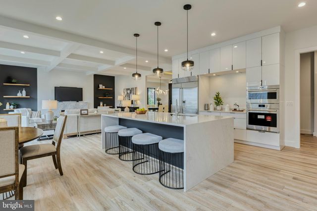a large kitchen with cabinets wooden floor stainless steel appliances and chairs