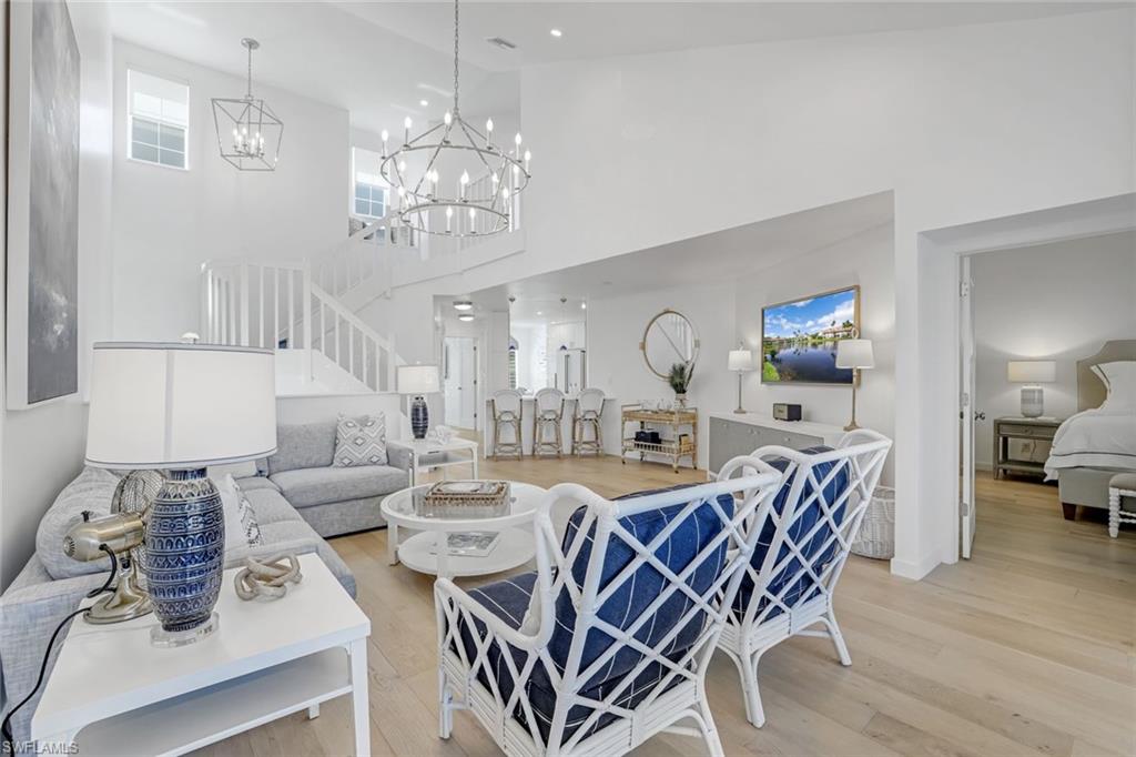 Living room with light wood-style floors, stairs, a towering ceiling, and recessed lighting
