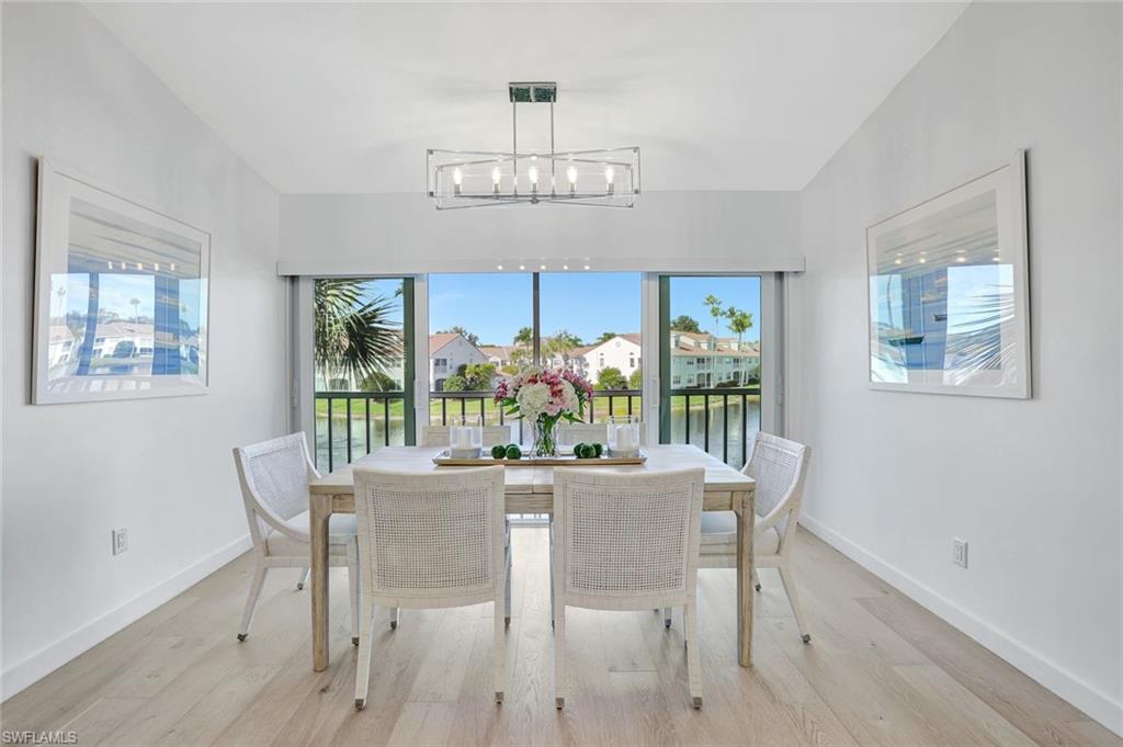 8345 Excalibur Circle, Unit M4 Naples, FL 34108 - Photo 4 of 19 a dining room with furniture a large window and wooden floor