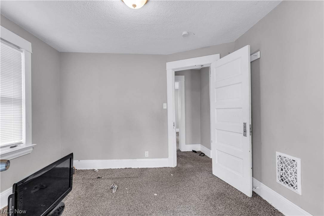 909 Stevenson Road Cleveland, OH 44110 - Photo 17 of 24 Empty room with dark colored carpet and a textured ceiling