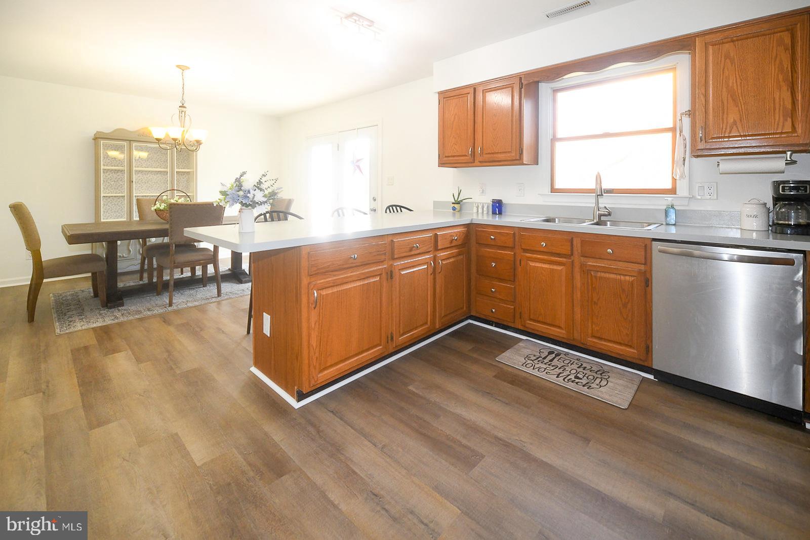 605 Planters Wharf Road Lusby, MD 20657 - Photo 7 of 45 a kitchen with stainless steel appliances granite countertop a sink dishwasher a stove a dining table and chairs with wooden floor