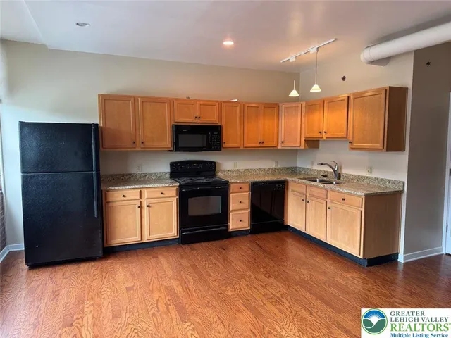 a view of kitchen with wooden floor and cabinets