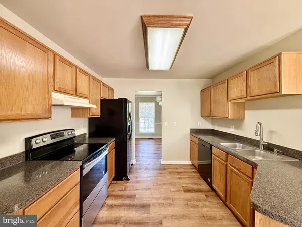 a kitchen with granite countertop a refrigerator a stove top oven and a sink
