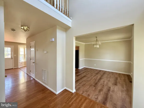 an empty room with wooden floor mirror and windows