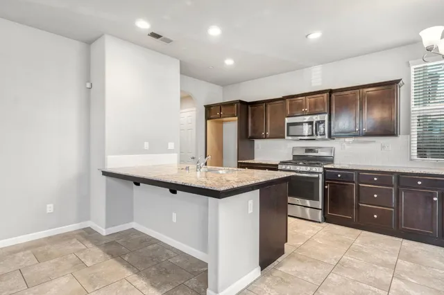 a kitchen with stainless steel appliances granite countertop a sink and stove top oven