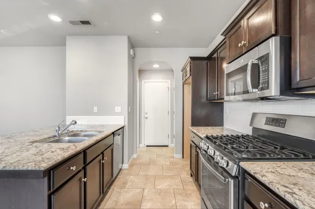 a kitchen with granite countertop stainless steel appliances a sink stove top oven and cabinets