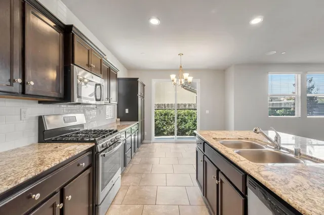 a kitchen with granite countertop stainless steel appliances a sink stove and cabinets