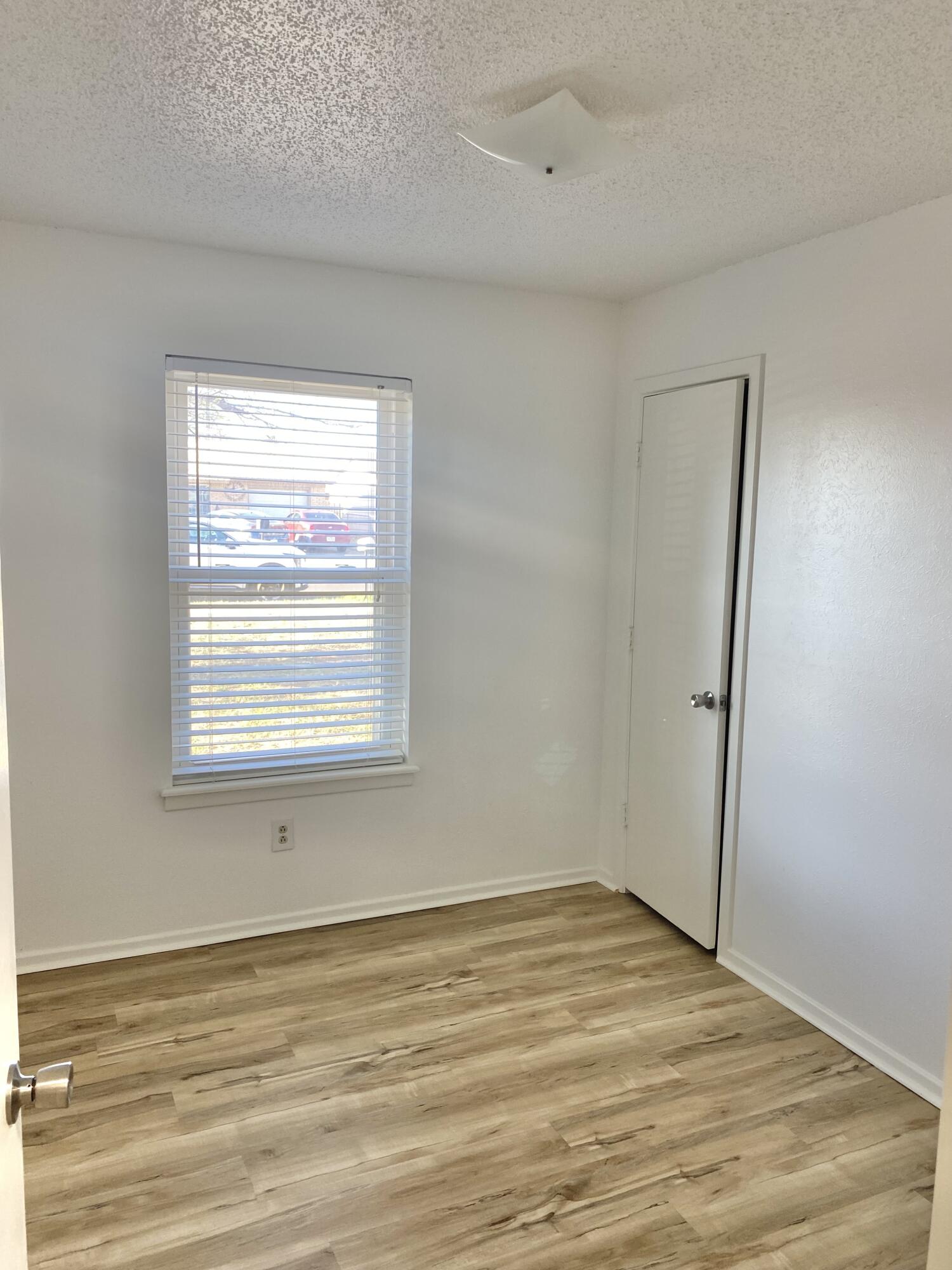2128 74th Street Lubbock, TX 79423 - Photo 13 of 15 a view of an empty room with wooden floor and a window