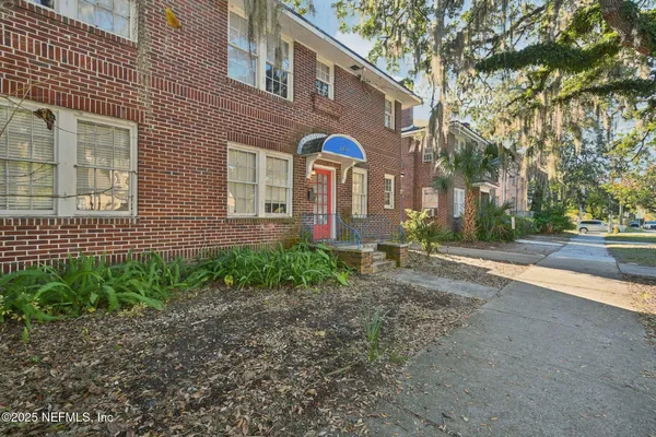 a view of a brick house with many windows next to a road