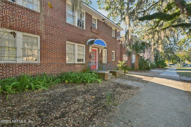 a view of a brick house with many windows next to a road