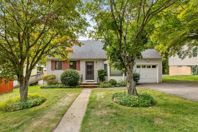a front view of a house with a garden and trees