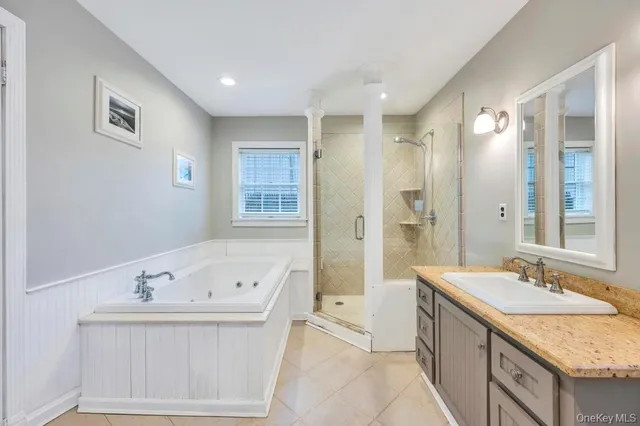 a bathroom with a tub sink double vanity and a mirror