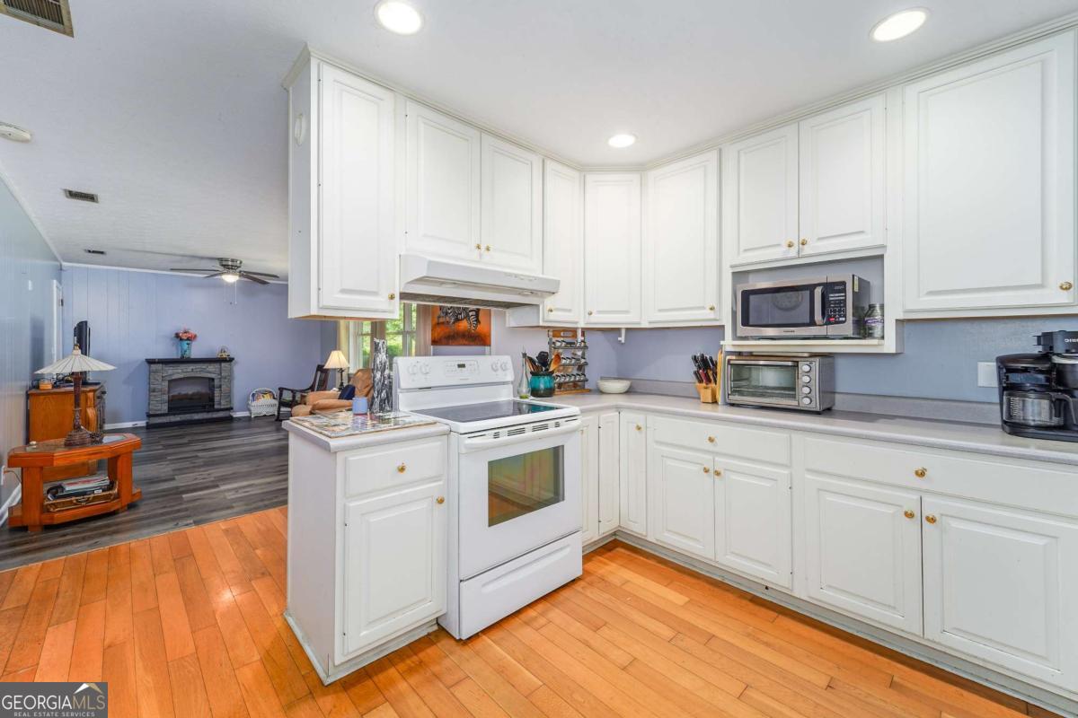 1703 Rainbow Drive Waycross, GA 31501 - Photo 6 of 19 a kitchen with stainless steel appliances granite countertop a stove a sink dishwasher and a microwave oven with white cabinets