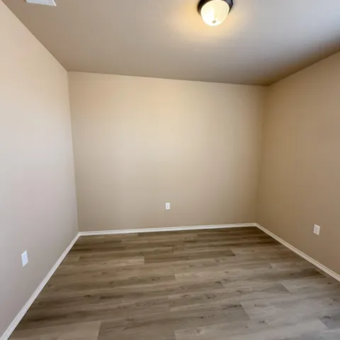 a view of an empty room with wooden floor and windows