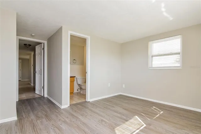a view of an empty room with window and wooden floor